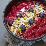 Açaí Bowl wird von oben in einer dunklen Schüssel gezeigt.