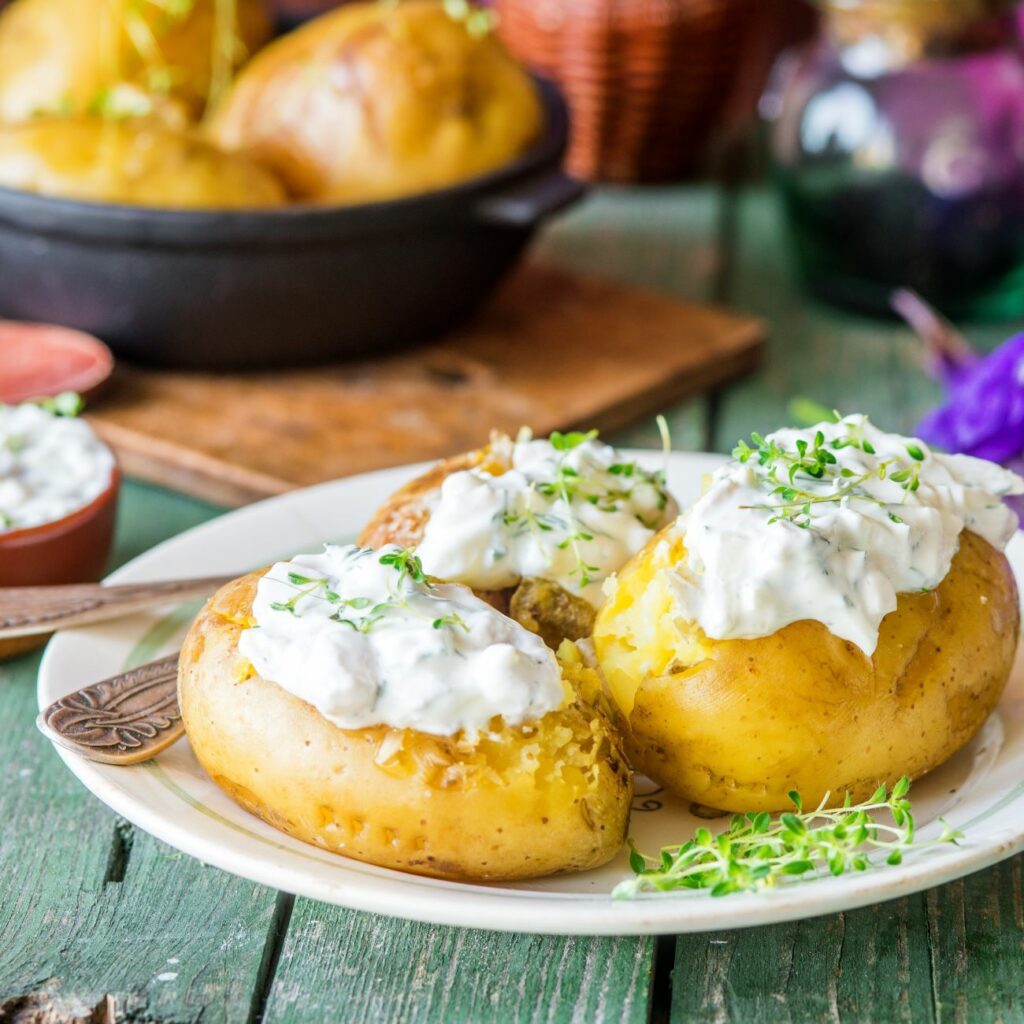 Skleněné brambory podávané se zakysanou smetanou na bílém talíři