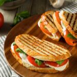 Panini Tomate Mozzarella werden auf einem Holzbrett serviert.