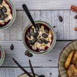 Vannile-Joghurt mit Kürbiskernen und karamellisierten Bananen wird in Gläsern serviert.