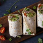 Angeschnittene Wraps mit Hähnchen und Avocado werden serviert mit Petersilie