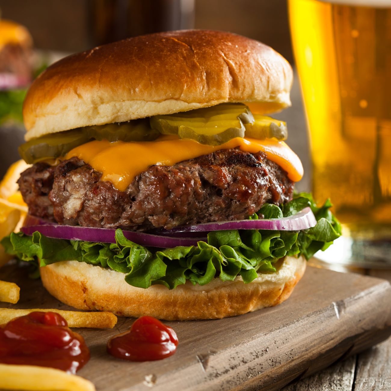 Cheeseburger je zobrazený zblízka a s hranolkami na boku.