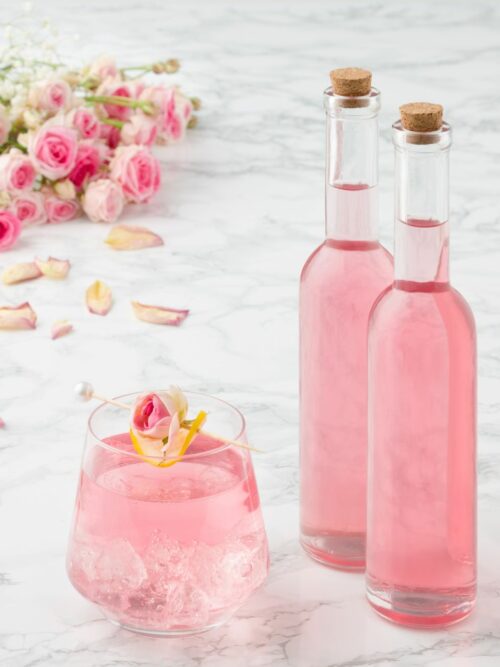 Ružový sirup sa podáva v dvoch malých fľašiach a pohári s kockami ľadu.