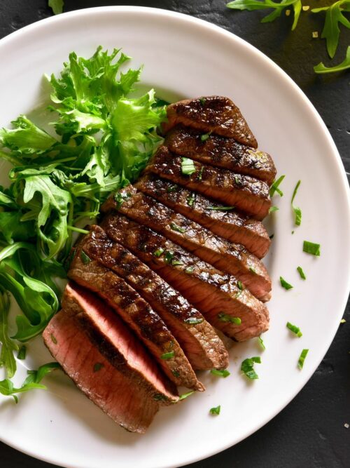 Steak z teplovzdušnej fritézy je znázornený nakrájaný zhora so šalátom.