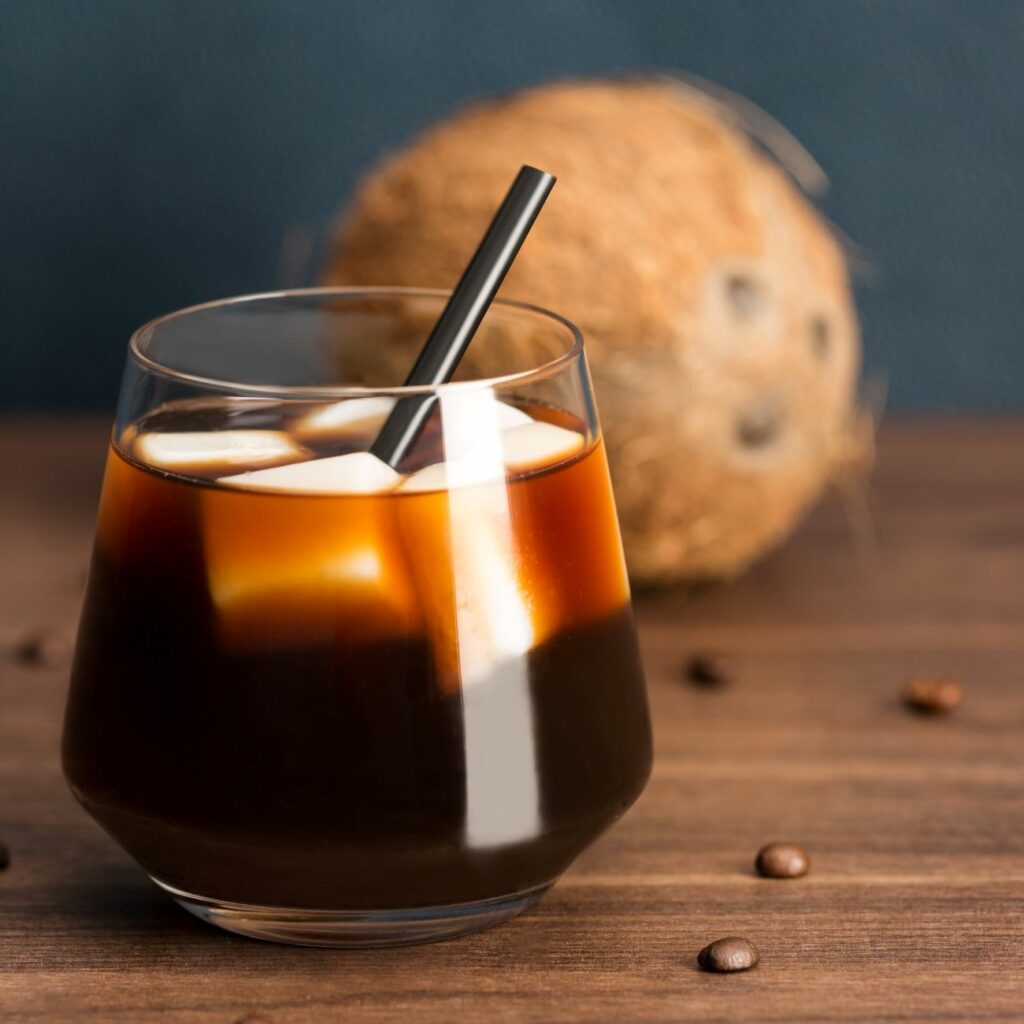 Káva s kockami ľadu z kokosového mlieka v pohári so slamkou.