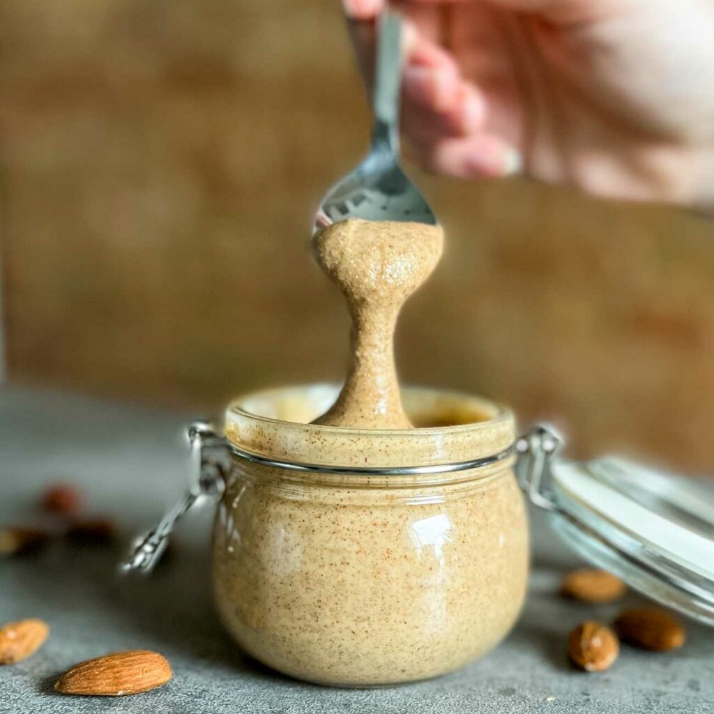Mandelmuss wird aus einem Weckglas mit einem Löffel herausgehoben.