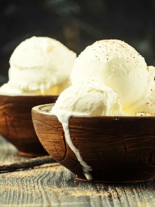 Veganes Vanilleeis wird in zwei hölzernen Schalen serviert.