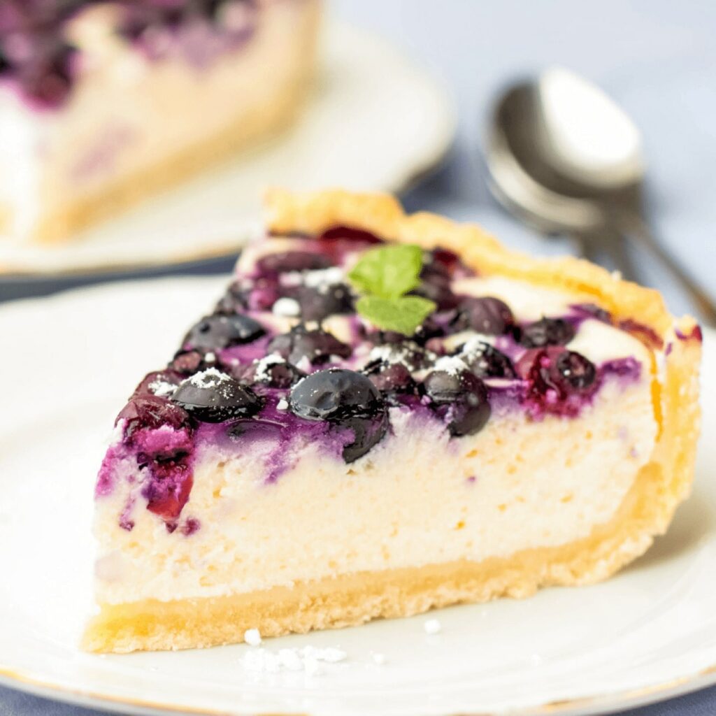 Blaubeer-Käsekuchen wird als Stück auf einem Kuchenteller gezeigt.