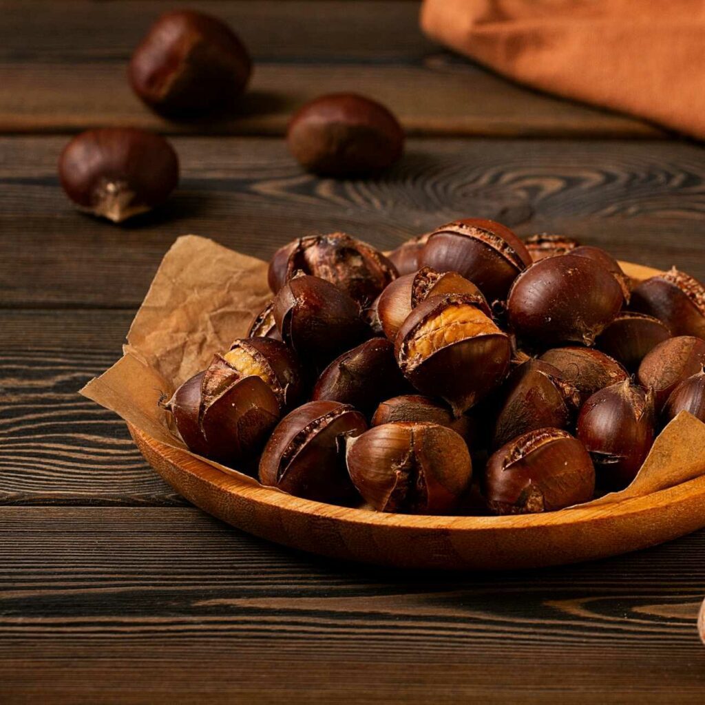 Maronen zubereiten: Geröstete Maronen werden in einer Holzschale mit Backpapier gezeigt.