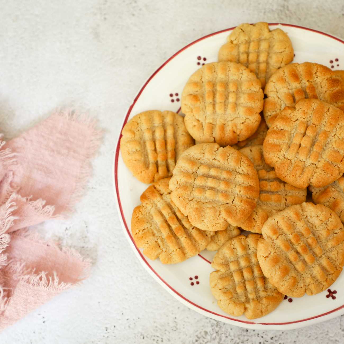 Erdnussbutter-Kekse werden auf einem kleinen Teller mit einem rosanen Tuch gezeigt.