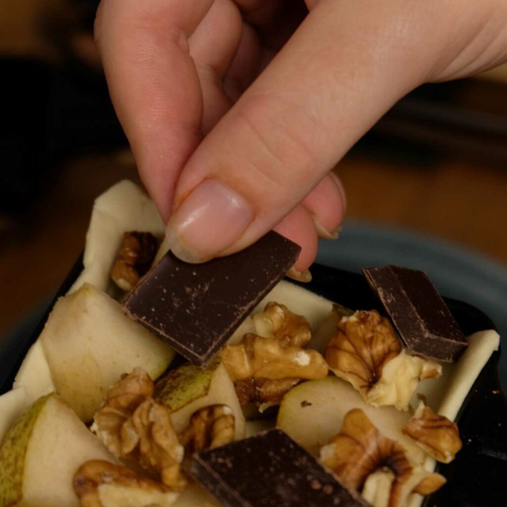 Quiche-Pfännchen wird mit Schokolade belegt.