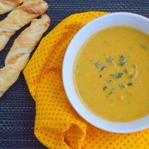 Kartoffel-Curry-Suppe wird mit Kräutern auf einem Tuch mit Brotstangen serviert.