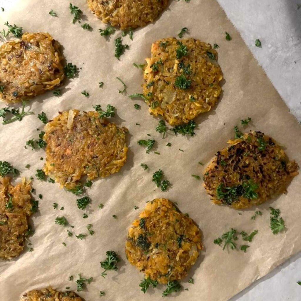 Süßkartoffelpuffer werden auf Backpapier ausgelegt gezeigt.