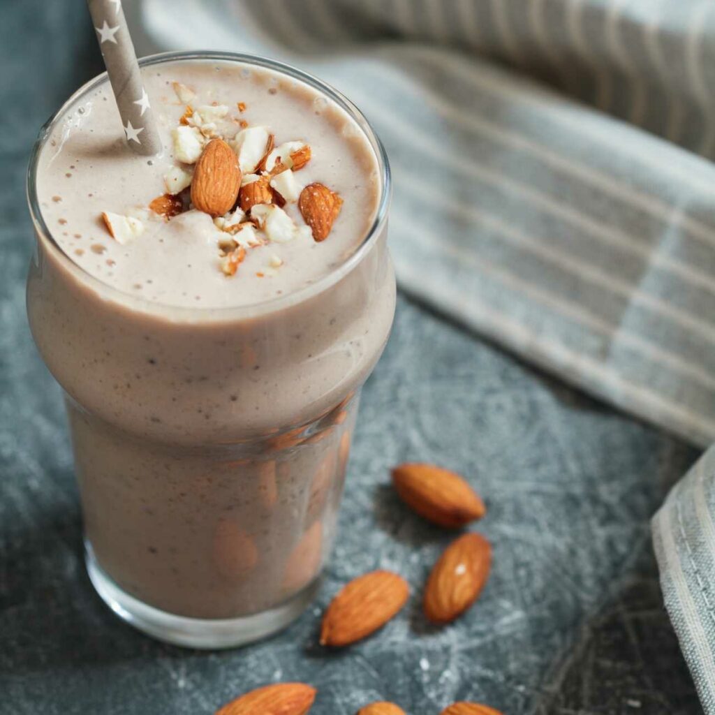 Mandel Smoothie wird mit einem Strohhalm und Mandeln serviert.