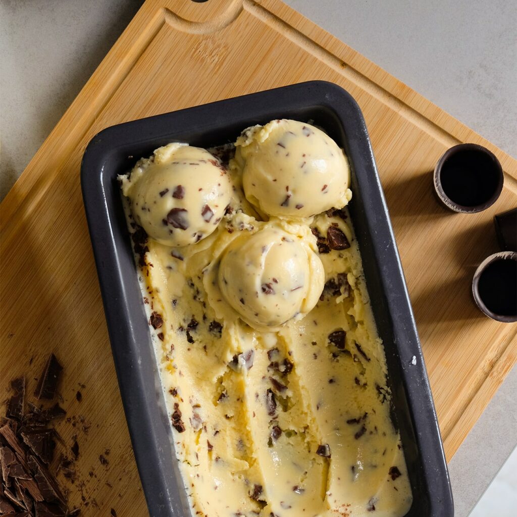 Sladoled z jajčnim likerjem je prikazan v posodi za sladoled. Oblikovane so 3 kepice.