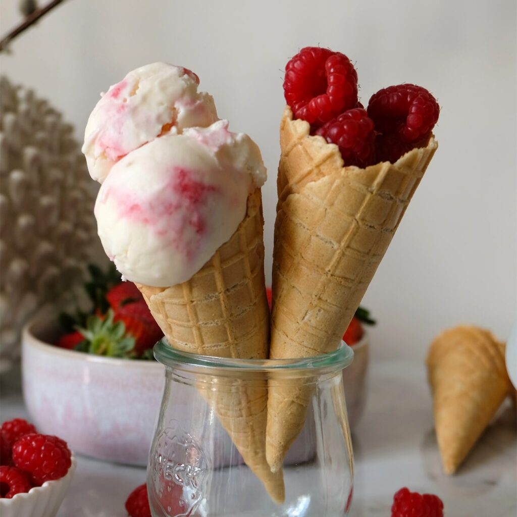 Malinová jogurtová zmrzlina je zobrazena v kornoutu na zmrzlinu.