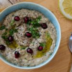 Baba Ganoush wird in einer kleinen, blauen Schüssel mit Granatapfelkernen und Petersilie gezeigt