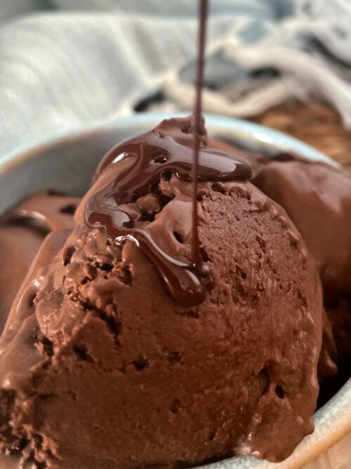 Dunkles Schokoladeneis wird gezeigt, während es mit flüssiger Schokolade begossen wird. 