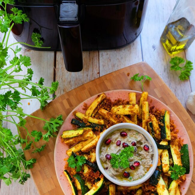 Zucchini Sticks werden auf einem Teller mit Baba Ganoush serviert.