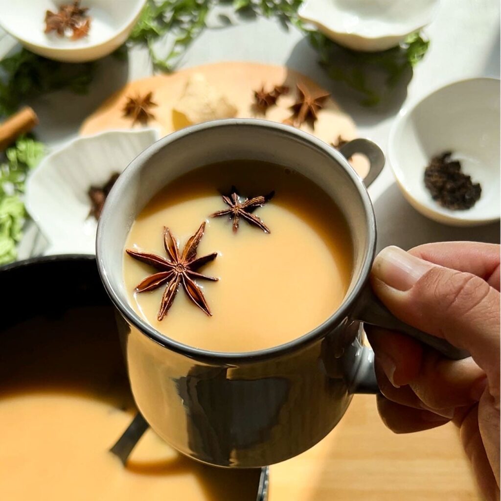 Herbatę Chai pokazano w filiżance z przyprawami w świetle słonecznym.